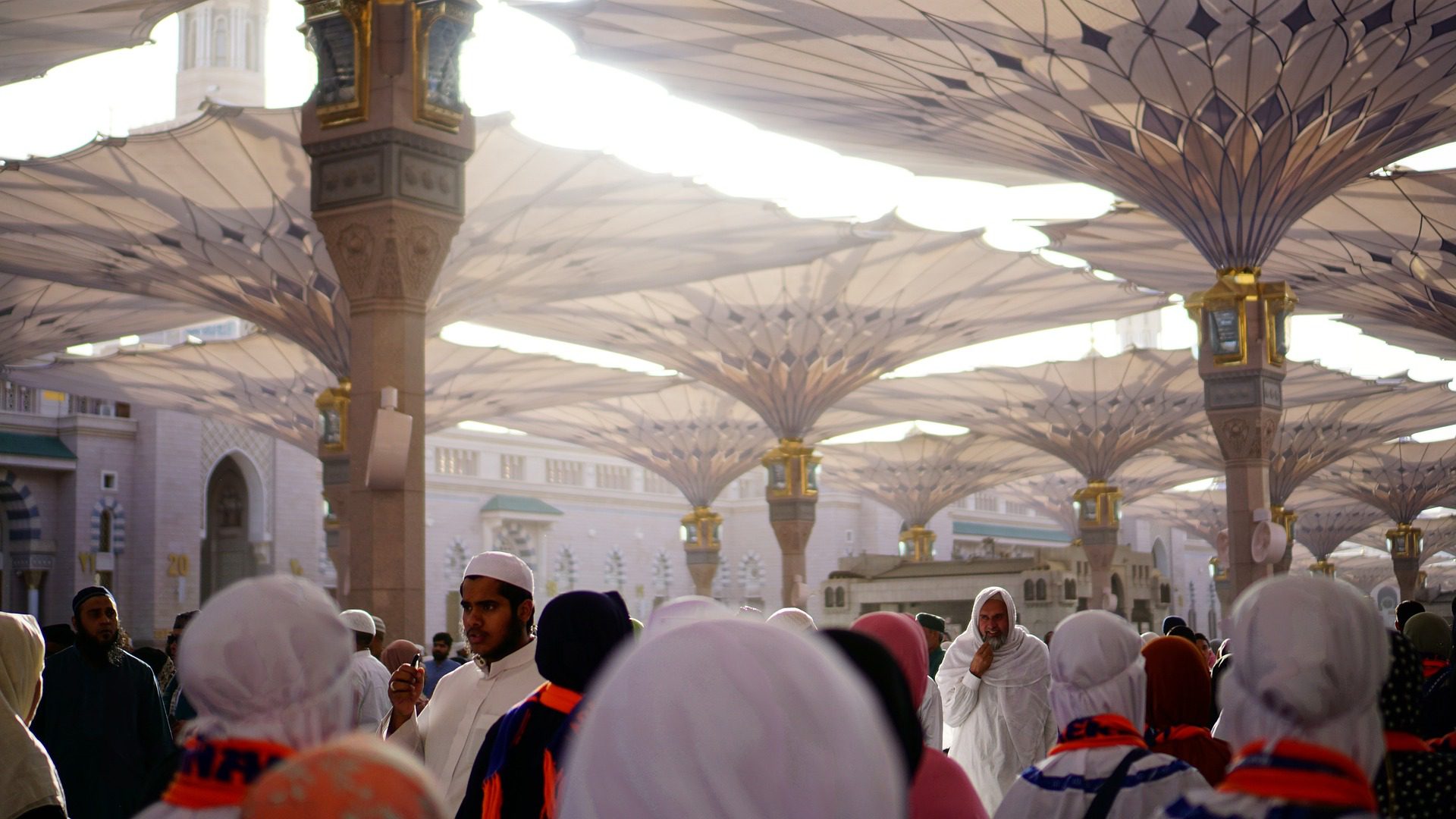 Pilgrims walking under the giant umbrellas at Masjid Nabawi in Madinah